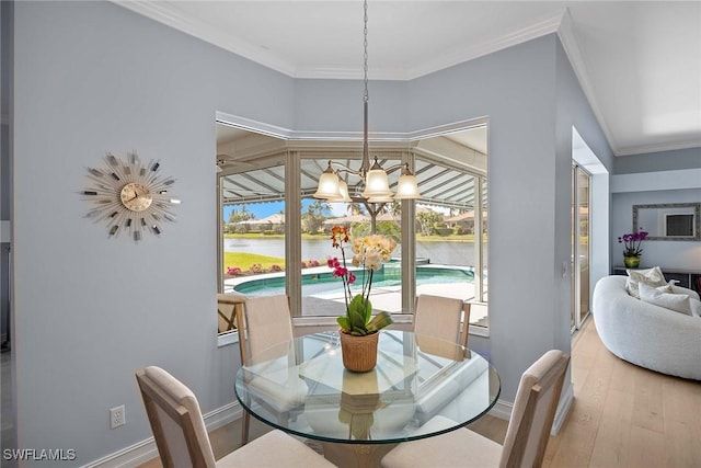 dining room with a notable chandelier, ornamental molding, hardwood / wood-style floors, and a water view