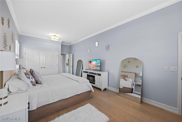 bedroom with hardwood / wood-style floors, crown molding, and a closet