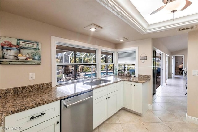 kitchen featuring sink, dark stone countertops, white cabinetry, light tile patterned flooring, and stainless steel dishwasher