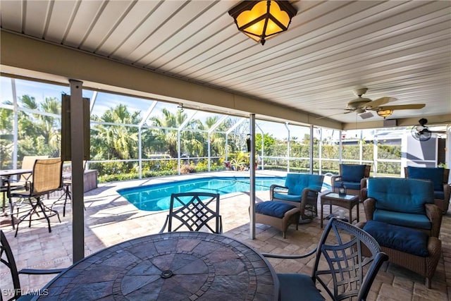 view of pool with outdoor lounge area, ceiling fan, a lanai, and a patio area