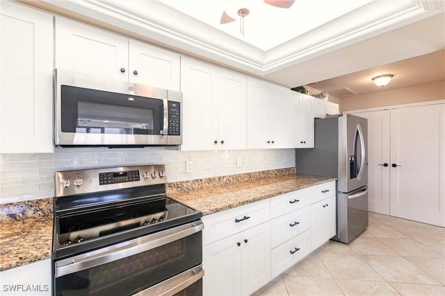 kitchen featuring light tile patterned flooring, appliances with stainless steel finishes, light stone countertops, decorative backsplash, and white cabinets