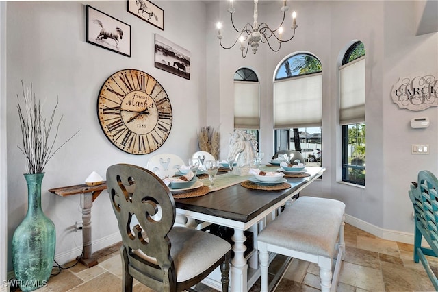 dining space featuring a towering ceiling and an inviting chandelier