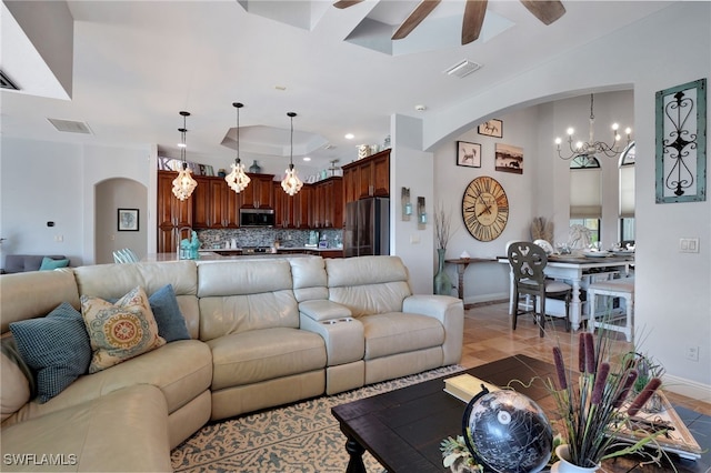 tiled living room with ceiling fan with notable chandelier