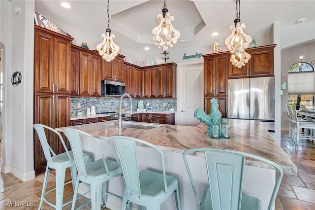 kitchen with hanging light fixtures, a raised ceiling, appliances with stainless steel finishes, and a large island