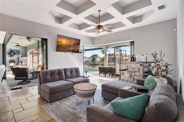 living room featuring coffered ceiling, decorative columns, ceiling fan, and a high ceiling