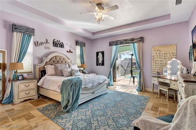 bedroom featuring ceiling fan, a tray ceiling, and access to outside