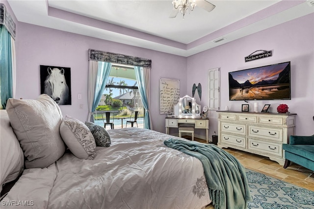 bedroom featuring access to outside and a tray ceiling