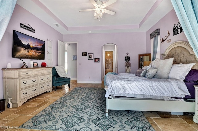 bedroom featuring a tray ceiling, ceiling fan, and ensuite bathroom