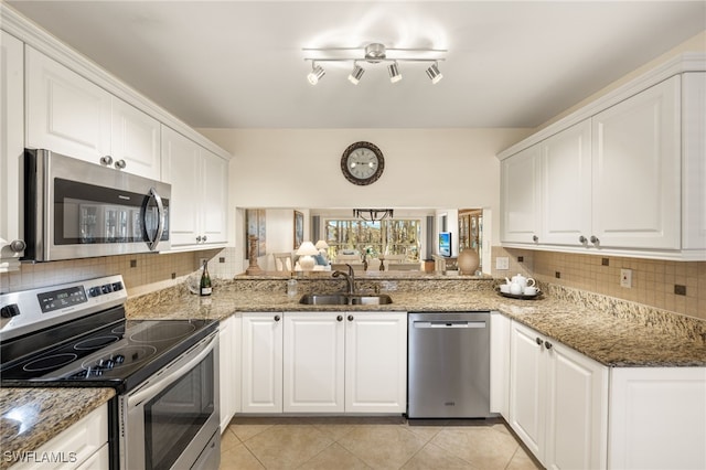 kitchen with sink, white cabinetry, stainless steel appliances, light tile patterned flooring, and dark stone counters