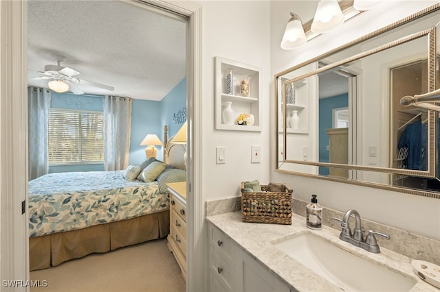 bathroom featuring ceiling fan, vanity, and a textured ceiling