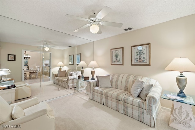 carpeted living room featuring ceiling fan and a textured ceiling