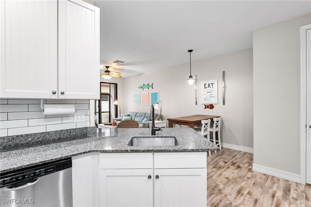 kitchen featuring pendant lighting, sink, dishwasher, white cabinetry, and dark stone counters