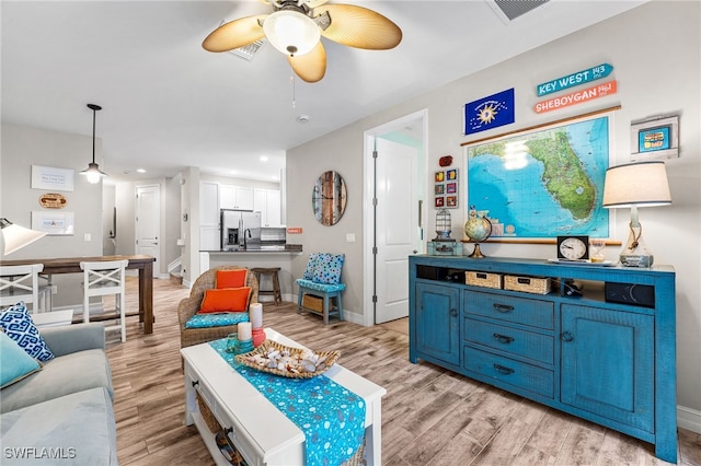 living room featuring sink, light hardwood / wood-style flooring, and ceiling fan