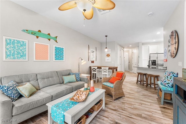 living room featuring ceiling fan, sink, and light hardwood / wood-style floors