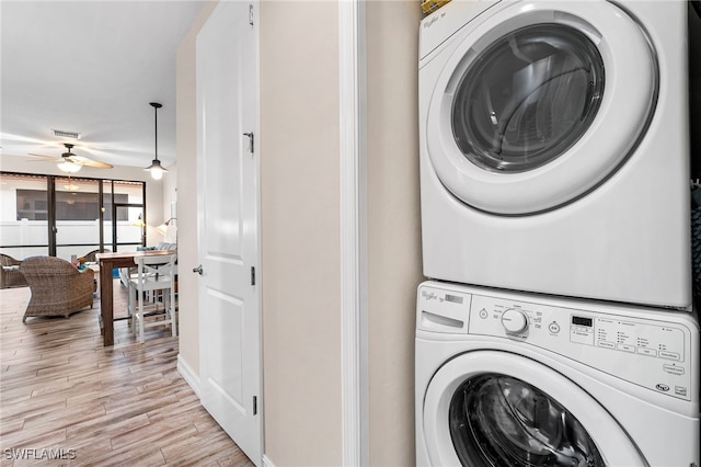 clothes washing area featuring stacked washer and clothes dryer, ceiling fan, and light hardwood / wood-style flooring