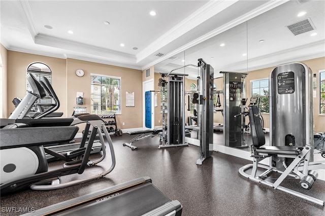 gym with a raised ceiling and crown molding