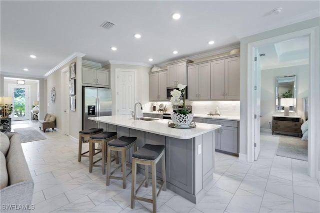 kitchen featuring light countertops, visible vents, gray cabinetry, appliances with stainless steel finishes, and a kitchen breakfast bar