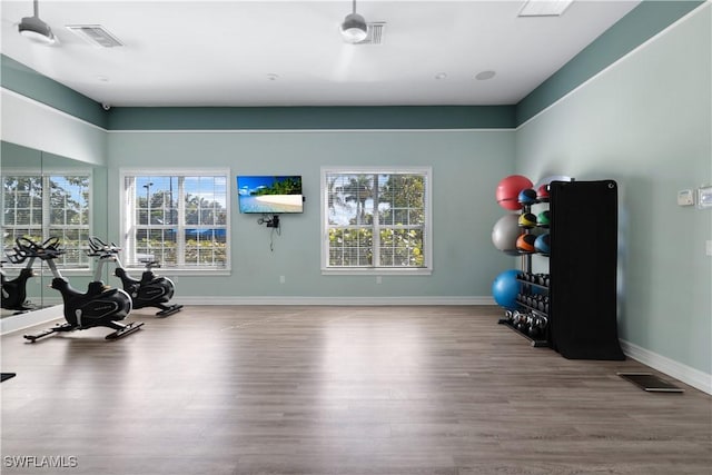 exercise area with visible vents, baseboards, and wood finished floors