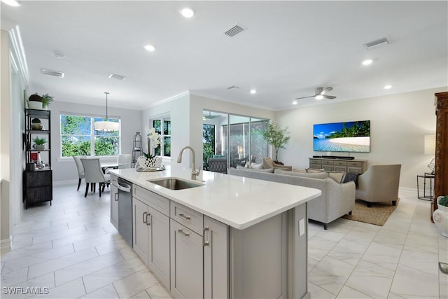 kitchen featuring a sink, light countertops, stainless steel dishwasher, hanging light fixtures, and a center island with sink