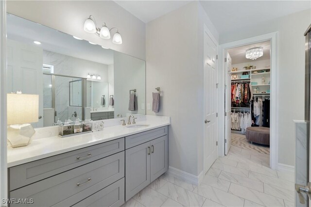 full bath featuring vanity, baseboards, marble finish floor, a spacious closet, and a shower stall