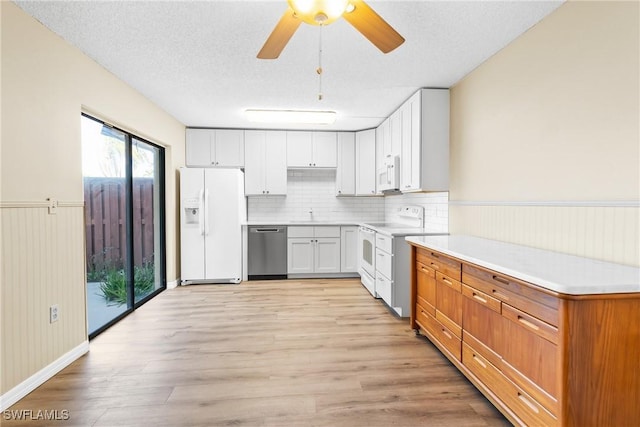 kitchen featuring white cabinetry, a textured ceiling, white appliances, and light hardwood / wood-style floors