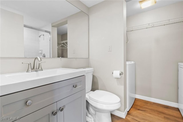 bathroom featuring vanity, a shower, hardwood / wood-style floors, and toilet