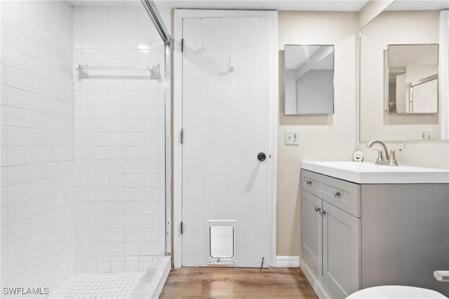 bathroom featuring wood-type flooring, vanity, and a tile shower