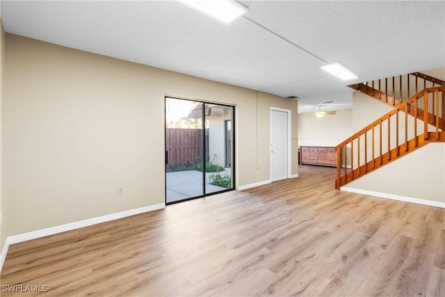 unfurnished living room featuring ceiling fan, light hardwood / wood-style flooring, and a textured ceiling