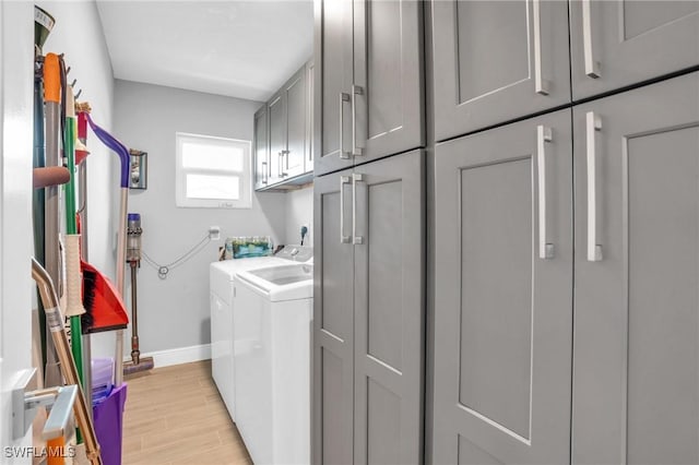 laundry room with cabinets, washer and clothes dryer, and light hardwood / wood-style flooring