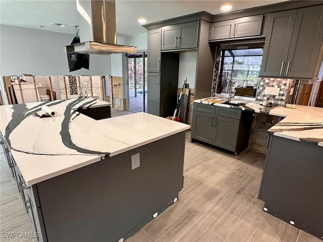 kitchen featuring island range hood, a center island, gray cabinetry, and light wood-type flooring