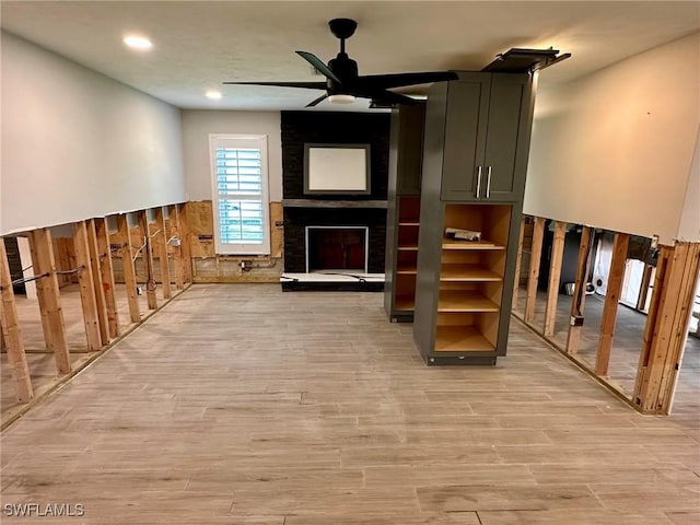 interior space with ceiling fan, light wood-type flooring, and a fireplace