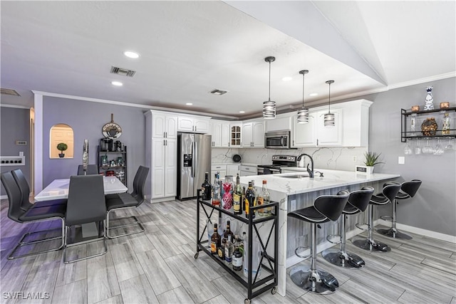 kitchen featuring decorative backsplash, a peninsula, stainless steel appliances, a kitchen bar, and a sink