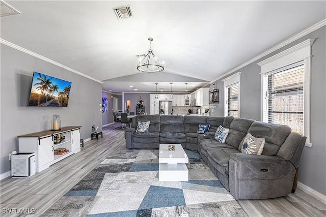 living room with a chandelier, visible vents, vaulted ceiling, ornamental molding, and light wood finished floors