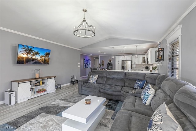 living area featuring ornamental molding, a notable chandelier, vaulted ceiling, and baseboards