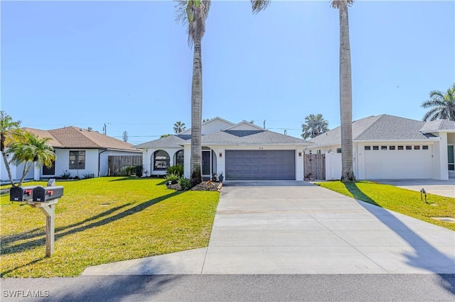 view of front of house with an attached garage, fence, driveway, stucco siding, and a front yard