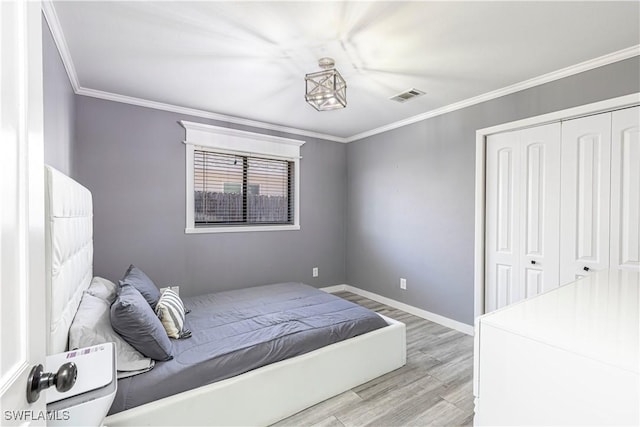 bedroom featuring crown molding, a closet, visible vents, wood finished floors, and baseboards