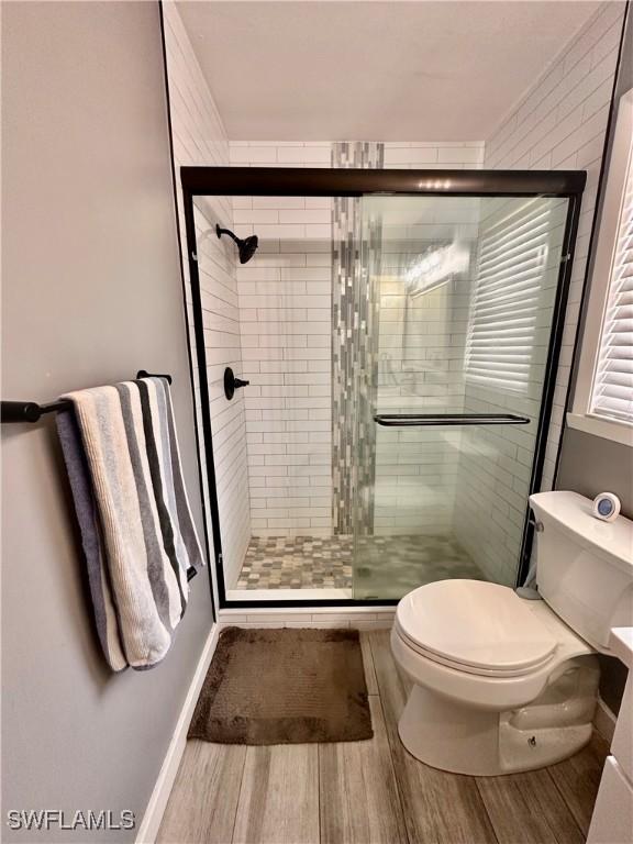 bathroom featuring a stall shower, wood finished floors, and toilet