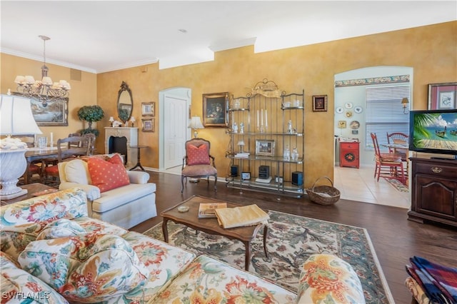 living room featuring wood-type flooring, ornamental molding, and an inviting chandelier