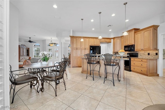 kitchen with light tile patterned floors, a kitchen island with sink, backsplash, black appliances, and decorative light fixtures