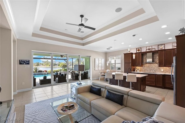 living room with a tray ceiling, ornamental molding, and ceiling fan