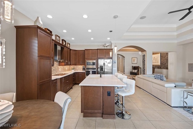 kitchen featuring light tile patterned flooring, tasteful backsplash, hanging light fixtures, a center island with sink, and stainless steel appliances