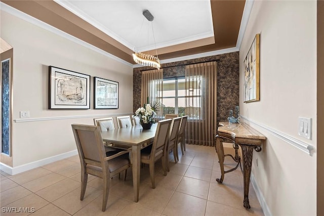 dining room with ornamental molding, a tray ceiling, and light tile patterned floors