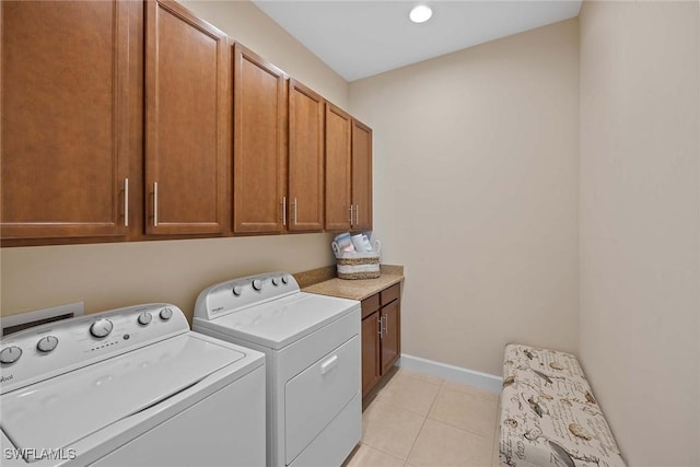 clothes washing area featuring cabinets, washer and dryer, and light tile patterned floors