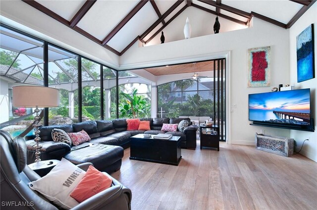 living room with hardwood / wood-style flooring, beamed ceiling, high vaulted ceiling, and a healthy amount of sunlight