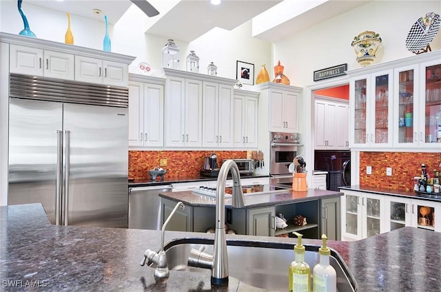 kitchen with sink, white cabinetry, a center island, stainless steel appliances, and decorative backsplash