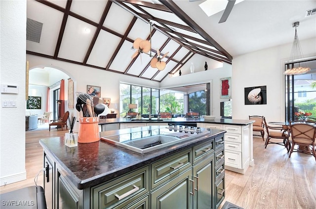 kitchen with light hardwood / wood-style flooring, black electric cooktop, a kitchen island, a healthy amount of sunlight, and white cabinets