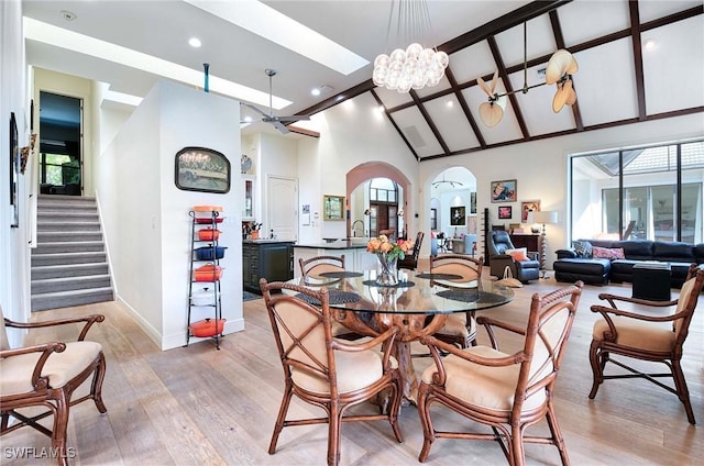 dining space featuring high vaulted ceiling, sink, light hardwood / wood-style floors, and a notable chandelier