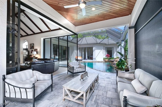 view of patio with an outdoor living space, ceiling fan, and glass enclosure