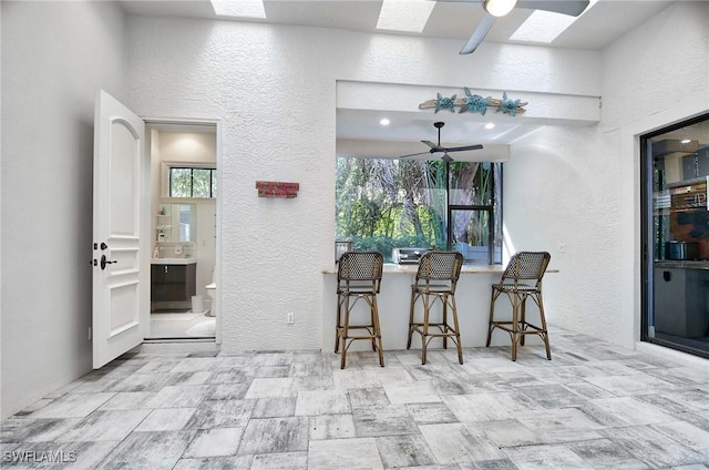 interior space with ceiling fan, a skylight, and a breakfast bar area