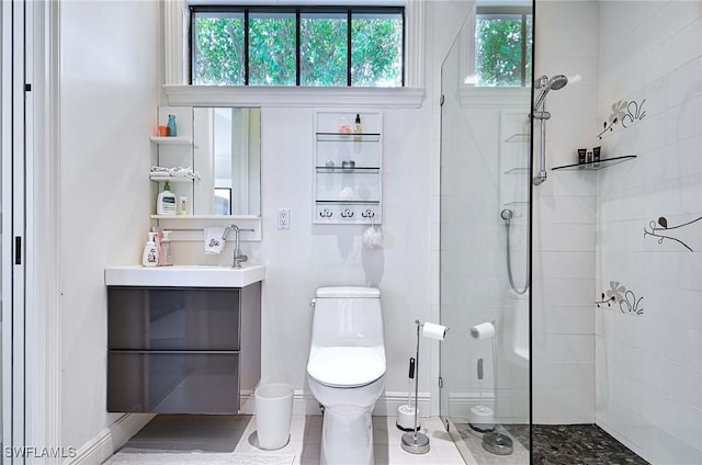 bathroom with tiled shower, vanity, and toilet